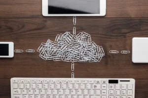 Office desk top-down view featuring a digital cloud formed by paperclips representing SD-WAN cloud intelligence.