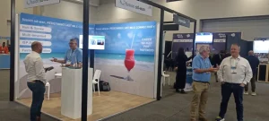 Professionals networking at an exhibition booth discussing last-mile SD-WAN deployment and connectivity.