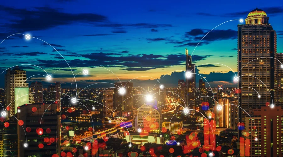 Illuminated city skyline at dusk overlaid with digital connection nodes representing SD-WAN for government networks.