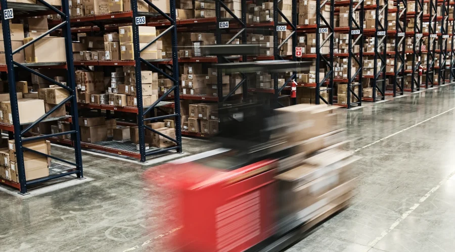Blurred forklift moving quickly through a large distribution warehouse relying on SD-WAN for logistics.